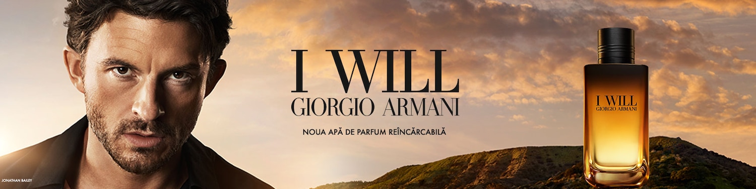 Jonathan Bailey, cu o privire intensă, este prezentat alături de sticla elegantă a parfumului Giorgio Armani „I Will”, pe un fundal cu un cer dramatic la apus și dealuri verzi.