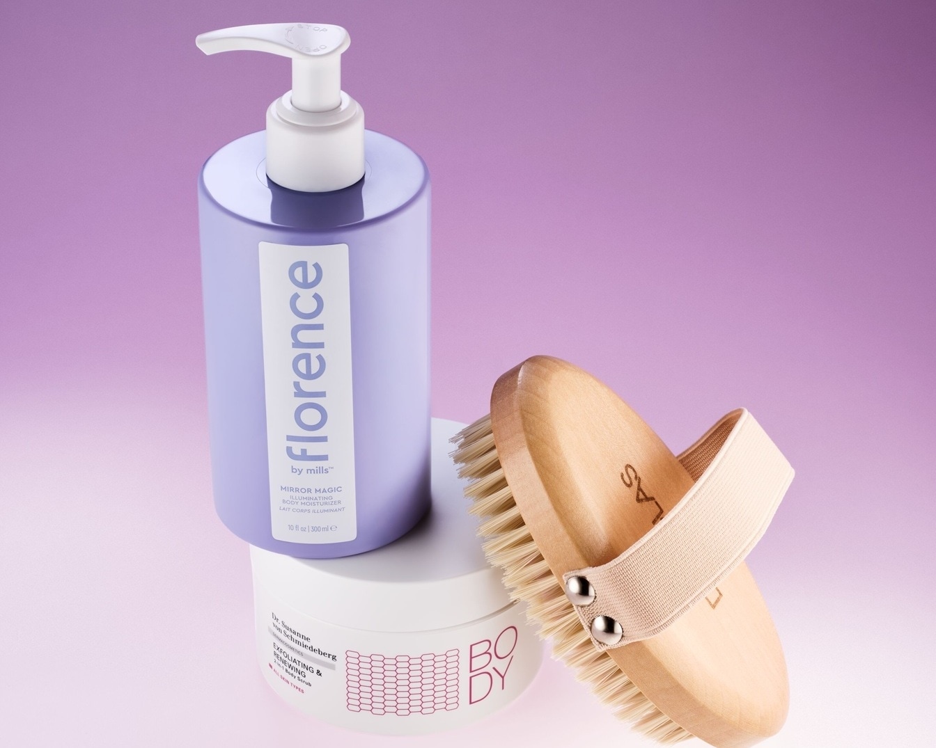 Setul de îngrijire corporală include o loțiune de corp Florence by Mills într-un recipient lavandă, un exfoliant de corp Dr. Susanne Von Schmiedeberg și o perie corporală din lemn, pentru o experiență ca la spa.