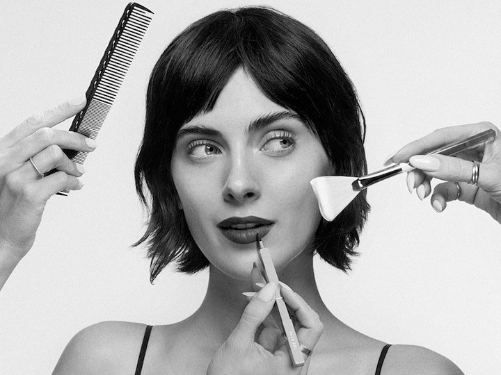 Un model este înconjurat de instrumente de frumusețe, inclusiv un pieptene și pensule de machiaj, evidențiind o rutină de îngrijire și înfrumusețare.